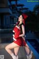 A woman in a red dress and a santa hat posing for a picture.