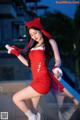 A woman in a red dress and hat posing for a picture.