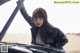 A woman standing next to a car in the desert.