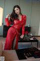 A woman in a red dress standing in front of a table.