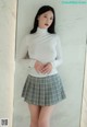 a woman in a white shirt and plaid skirt posing for a picture