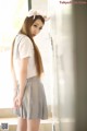 A woman in a white shirt and gray skirt posing for a picture.