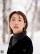 A woman in a black coat standing in the snow.