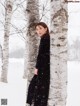 A woman leaning against a tree in the snow.