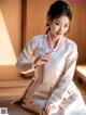 A woman in a white hanbok sitting on the floor.