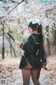 A woman in a black dress holding a samurai sword.
