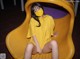 A woman wearing a yellow shirt and a face mask sitting on a yellow slide.