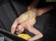 A woman in a yellow bikini laying in the back seat of a car.