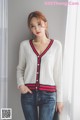 a woman wearing a white sweater and jeans posing for a picture