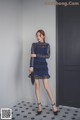 A woman in a blue dress standing in front of a door.