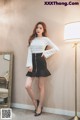 a woman standing in front of a mirror wearing a white shirt and black skirt