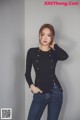 A woman wearing a black sweater and jeans posing for a picture.