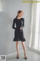 a woman in a black dress standing in front of a window