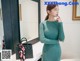 a woman in a green dress standing in front of a mirror