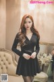 A woman in a black dress standing in front of a mirror.