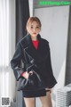 a woman wearing a black coat and a red top