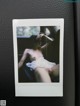 A polaroid photo of a naked woman sitting in a car.