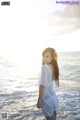 A woman standing in the ocean with a flower in her hair.