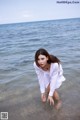 A woman in a white shirt is standing in the water.