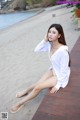 A woman sitting on a wooden boardwalk next to the ocean.