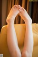 A woman's bare feet sitting on a yellow chair.