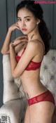 A woman in a red lingerie sitting on a white chair.