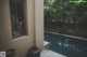 A woman is looking out of a window at a pool.