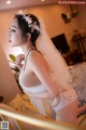 A woman in a wedding dress is posing on a bed.