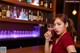 A woman sitting at a bar holding a glass of wine.