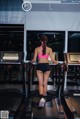 A woman in a pink top and black shorts running on a treadmill.