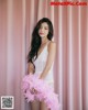 A woman in a white lingerie holding a pink feather boa.