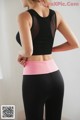 A woman in a black top and pink leggings.