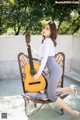 A woman sitting on a chair holding a guitar.