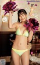 A woman in a bikini holding pom poms in her hands.