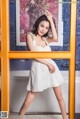 A woman in a white dress posing in a bathroom.