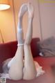 A woman in white stockings is laying on a red couch.