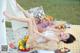 A woman laying on a blanket in a field with a picnic basket.