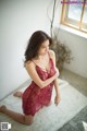 A woman in a red lingerie sitting on a white rug.