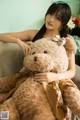 A woman sitting on a couch holding a large teddy bear.