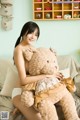 A woman sitting on a couch holding a large teddy bear.