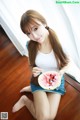 A woman sitting on the floor eating a slice of watermelon.