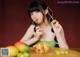 A woman sitting at a table eating a bowl of fruit.