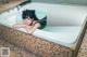 A woman laying in a bathtub with a cat mask on.