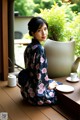 A woman in a kimono sitting on a wooden table.