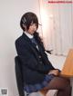 A woman in a school uniform sitting at a desk.