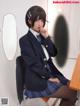 A woman in a school uniform sitting at a desk.