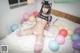 A woman in lingerie sitting on a bed surrounded by balloons.