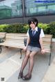 A woman sitting on a bench wearing a school uniform.