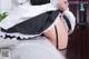 A woman in a maid outfit is putting on her panties.