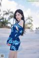 A woman in a blue and white floral dress posing for a picture.